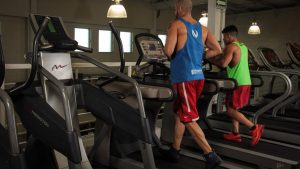 Two men running on treadmills in a modern gym, promoting fitness and health.